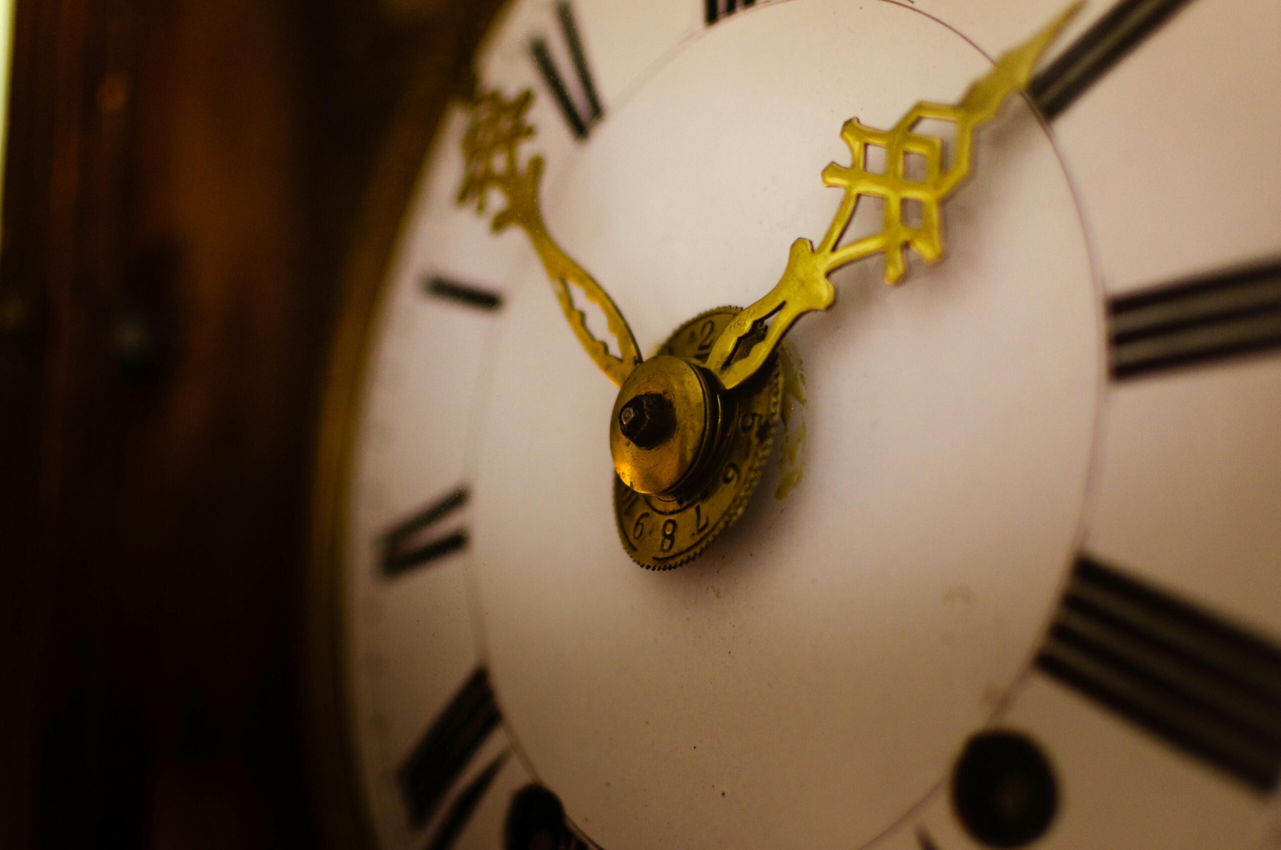 Detailed view of an antique clock face with ornate golden hands and Roman numerals.